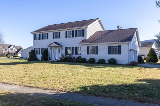 colonial house featuring a front lawn and a garage