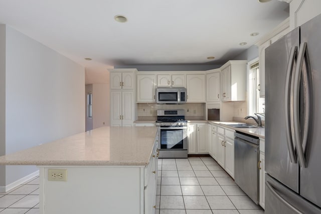 kitchen featuring sink, white cabinetry, light tile patterned floors, appliances with stainless steel finishes, and a kitchen island