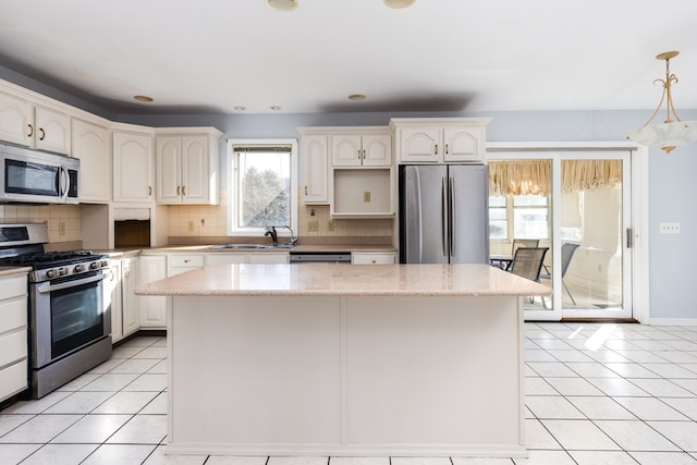 kitchen featuring appliances with stainless steel finishes, a kitchen island, sink, and hanging light fixtures