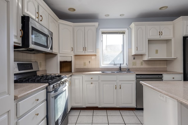 kitchen featuring tasteful backsplash, white cabinetry, sink, light tile patterned floors, and stainless steel appliances