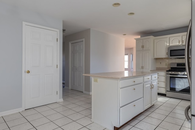 kitchen featuring backsplash, stainless steel appliances, white cabinets, and a kitchen island