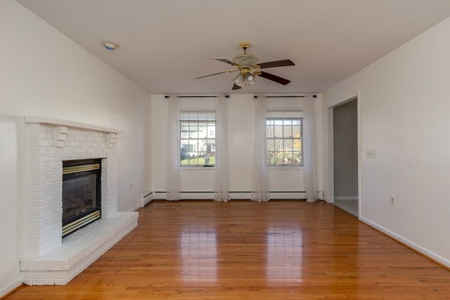 unfurnished living room with a brick fireplace, a baseboard heating unit, ceiling fan, and light hardwood / wood-style flooring