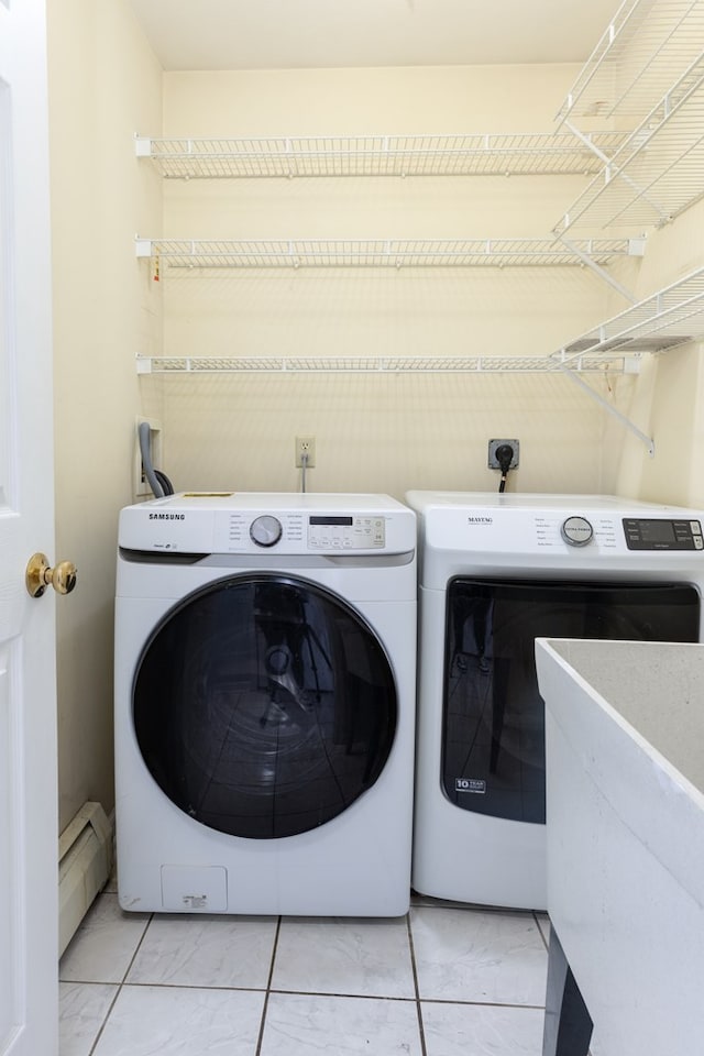 clothes washing area with washing machine and dryer, a baseboard heating unit, and light tile patterned floors