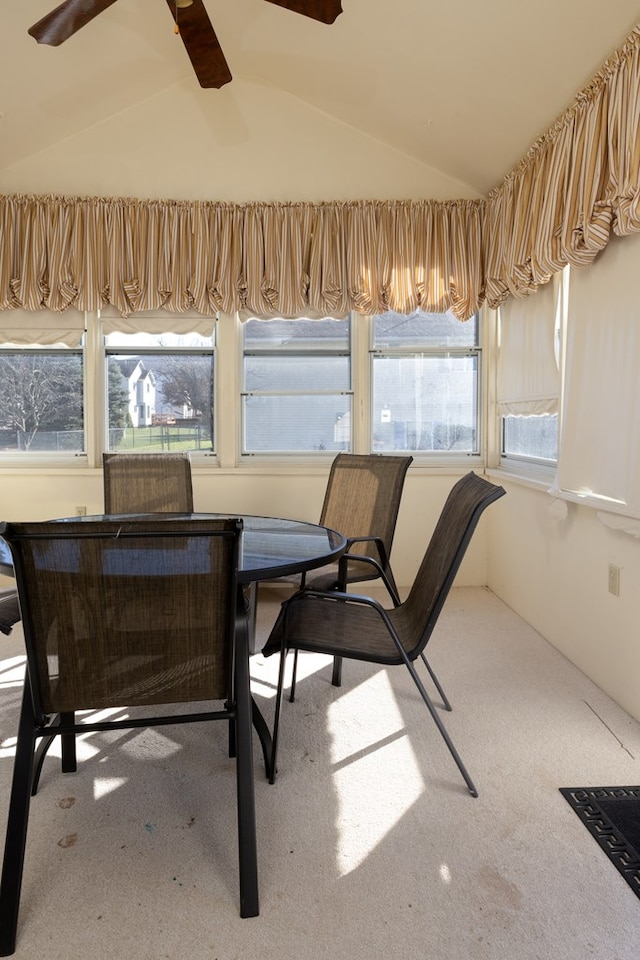 carpeted dining space with vaulted ceiling and ceiling fan