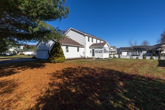 rear view of property with a garage, a sunroom, and a lawn