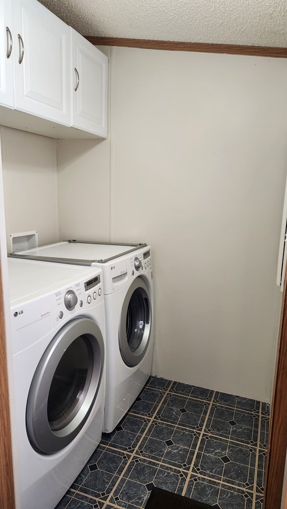 clothes washing area featuring cabinets, a textured ceiling, ornamental molding, and washing machine and clothes dryer