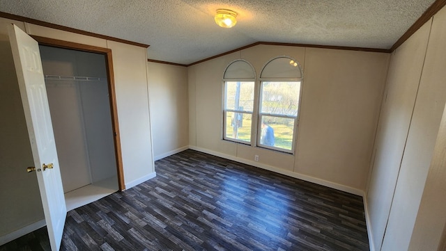 unfurnished bedroom with a textured ceiling, crown molding, dark wood-type flooring, and vaulted ceiling