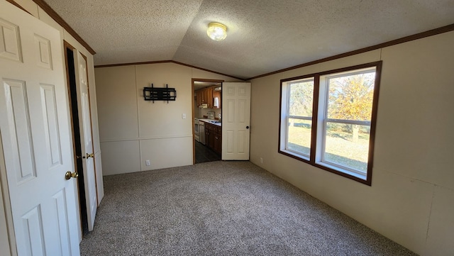 unfurnished bedroom featuring a textured ceiling, carpet floors, crown molding, and lofted ceiling