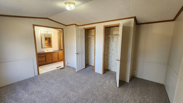 unfurnished bedroom with a textured ceiling, two closets, and lofted ceiling