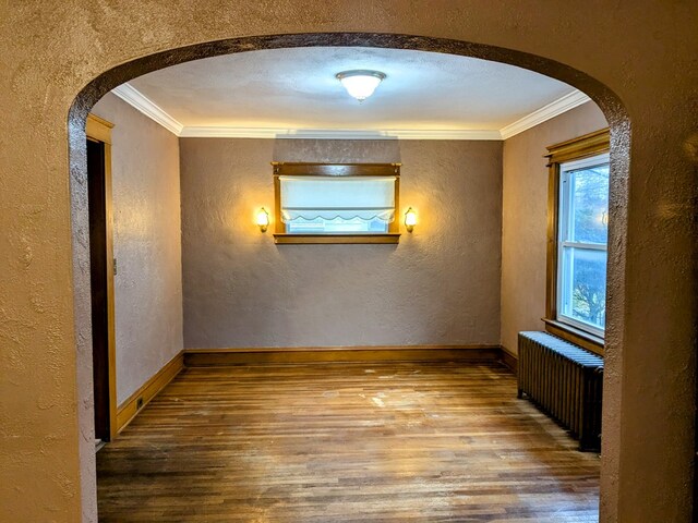 spare room featuring wood-type flooring, radiator, and crown molding