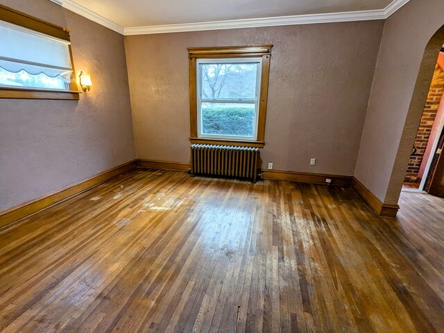 spare room with dark hardwood / wood-style floors, radiator, and ornamental molding