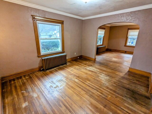 unfurnished room featuring wood-type flooring, radiator, and ornamental molding