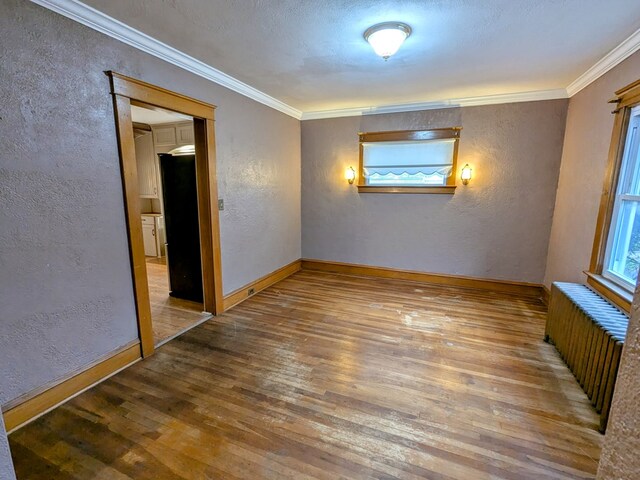 spare room featuring wood-type flooring, radiator, and crown molding