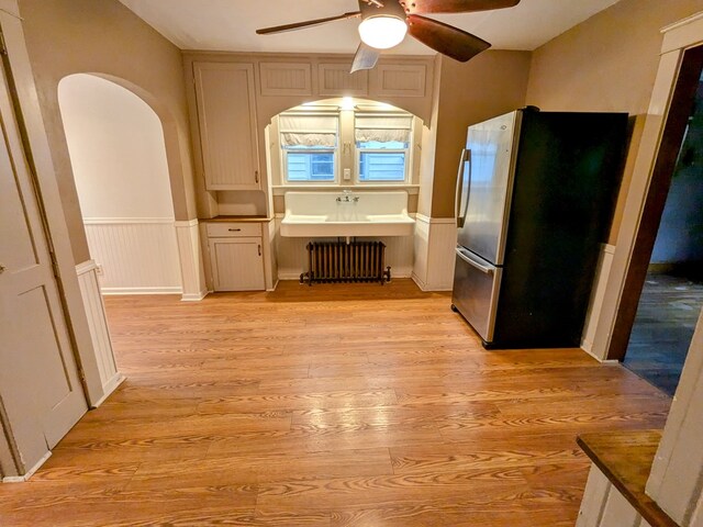 kitchen featuring radiator, stainless steel fridge, ceiling fan, and light wood-type flooring