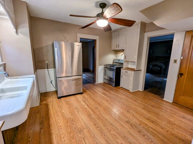 kitchen with white cabinets, light wood-type flooring, stainless steel appliances, and butcher block counters