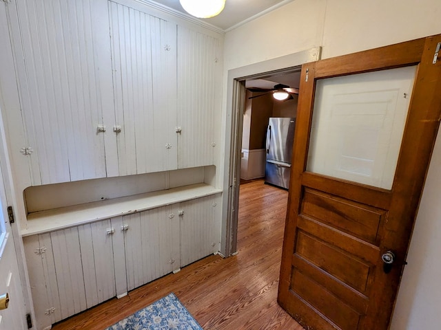 interior space with ornamental molding, light hardwood / wood-style floors, and white cabinets