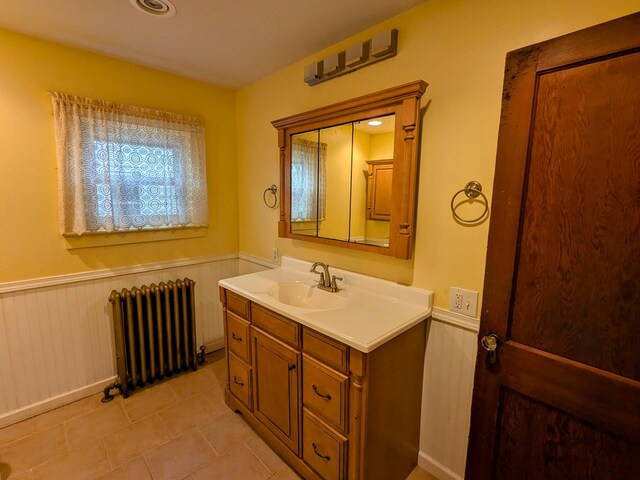 bathroom with tile patterned flooring, vanity, radiator, and wooden walls