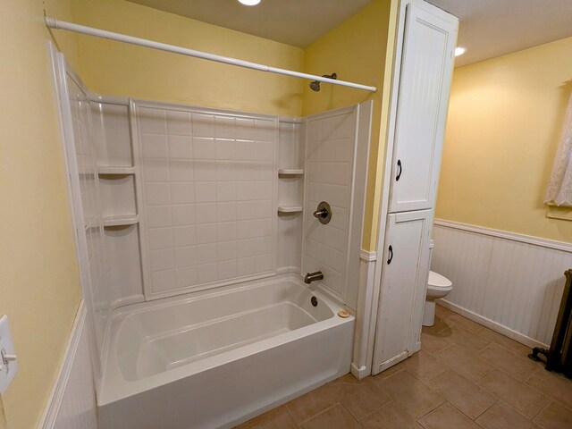 bathroom featuring tile patterned flooring, toilet, and shower / washtub combination