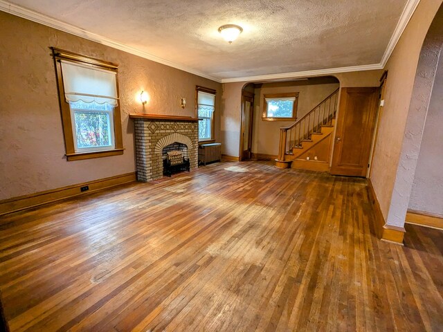 unfurnished living room with a fireplace, radiator heating unit, a textured ceiling, and ornamental molding