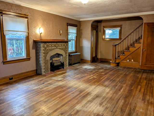 unfurnished living room with crown molding, plenty of natural light, wood-type flooring, and radiator heating unit