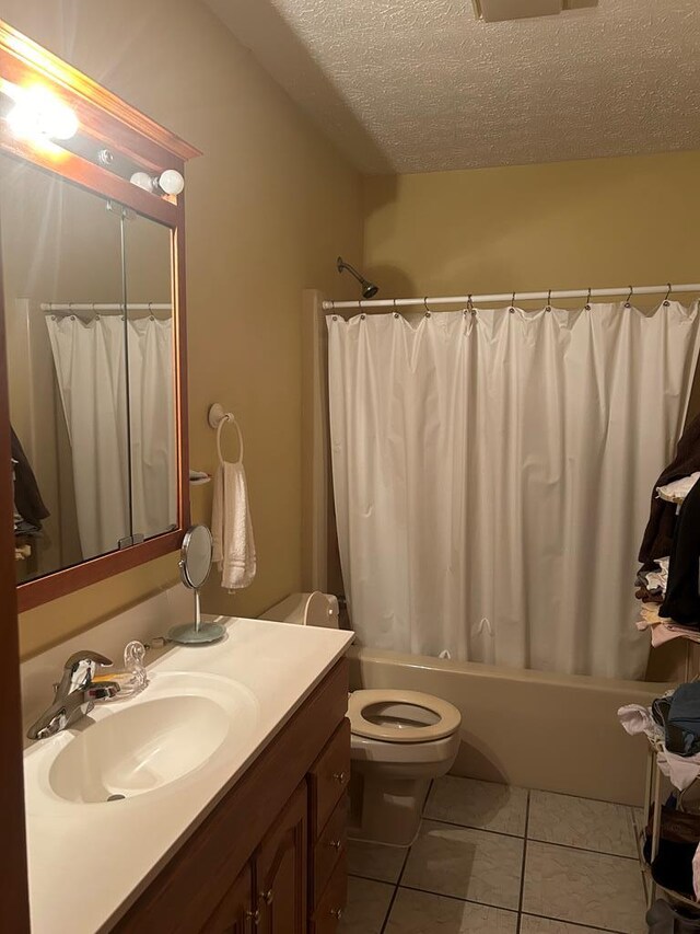 full bathroom with shower / bath combo, vanity, a textured ceiling, tile patterned flooring, and toilet