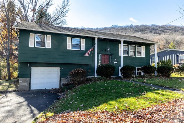 bi-level home featuring a garage and a front lawn