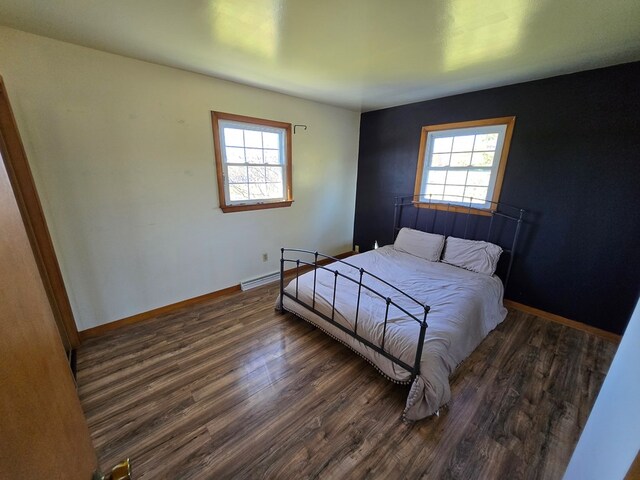 bedroom with dark hardwood / wood-style floors and multiple windows