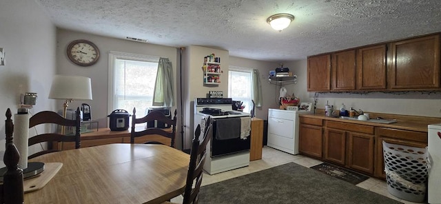 kitchen featuring white electric range, a textured ceiling, washer / dryer, and sink