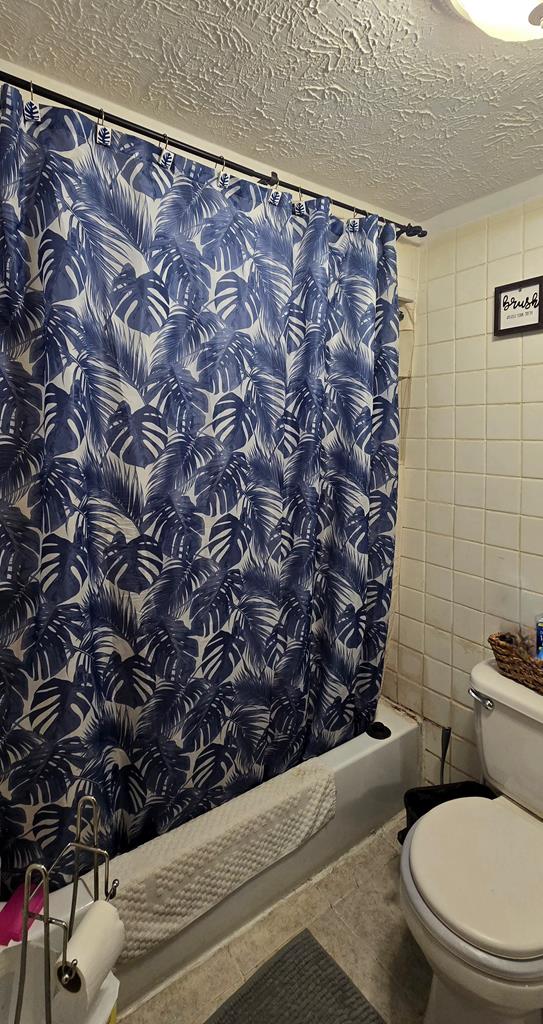 bathroom featuring tile patterned floors, a shower with curtain, a textured ceiling, and toilet