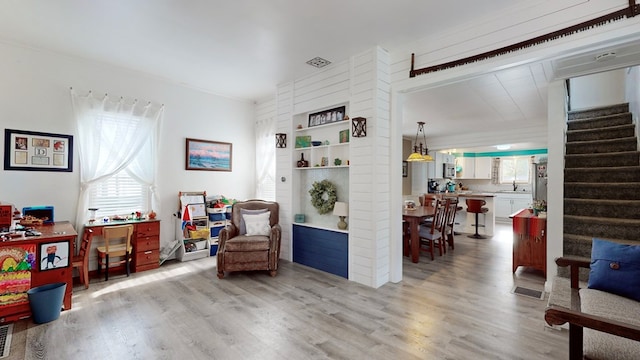 living area with light hardwood / wood-style floors, built in features, and sink