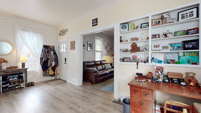 interior space with plenty of natural light, crown molding, and light hardwood / wood-style flooring