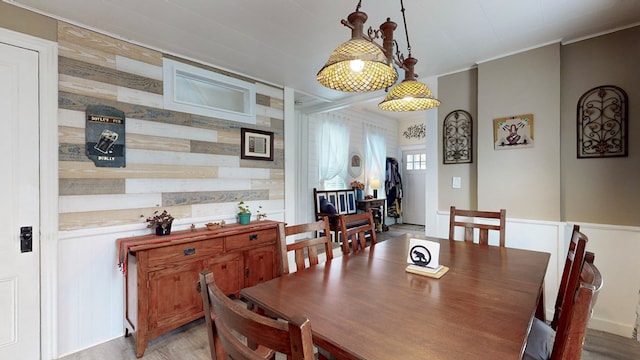 dining space featuring light wood-type flooring and wooden walls