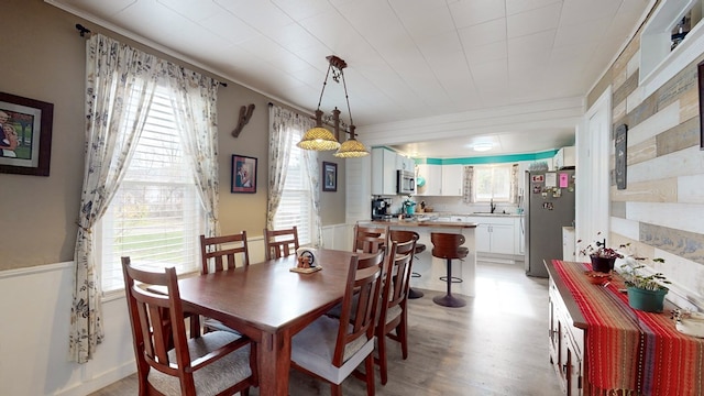 dining space featuring light hardwood / wood-style flooring, crown molding, and sink