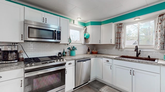 kitchen with backsplash, white cabinets, sink, hardwood / wood-style flooring, and stainless steel appliances