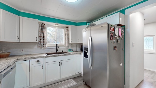 kitchen featuring stainless steel refrigerator with ice dispenser, dishwashing machine, sink, white cabinets, and light hardwood / wood-style floors