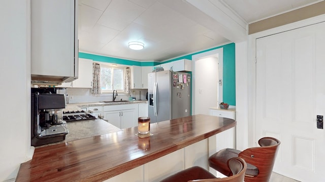 kitchen featuring white cabinets, sink, stainless steel refrigerator with ice dispenser, tasteful backsplash, and butcher block countertops