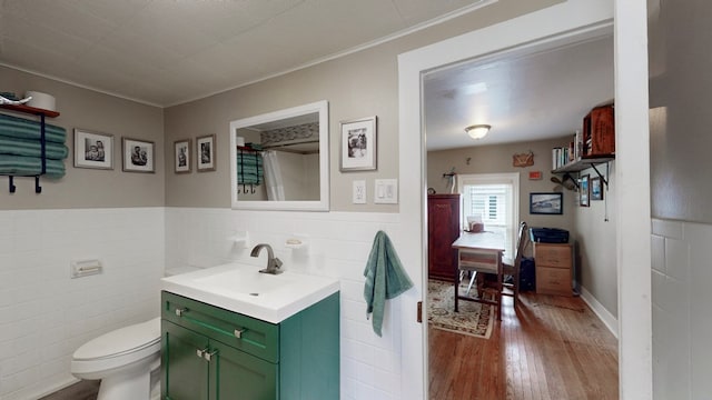 bathroom with toilet, vanity, tile walls, and hardwood / wood-style flooring