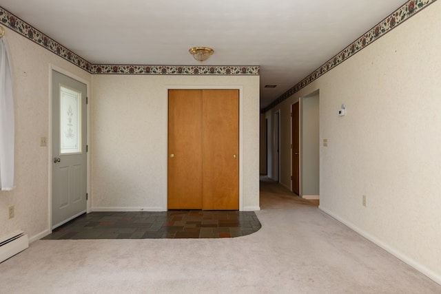 carpeted spare room featuring a baseboard heating unit