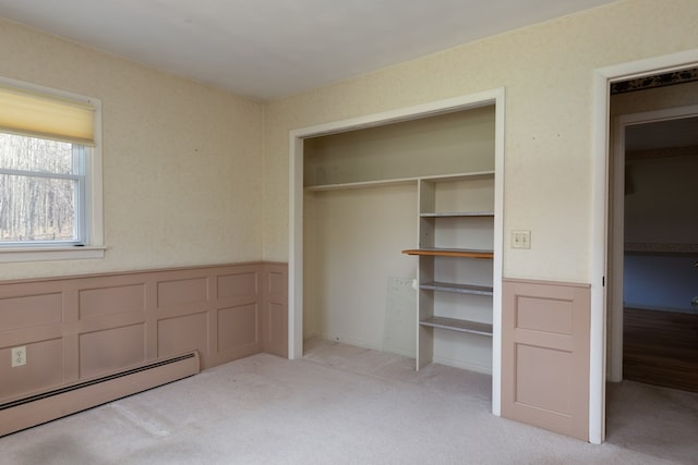 unfurnished bedroom featuring baseboard heating, light carpet, and a closet