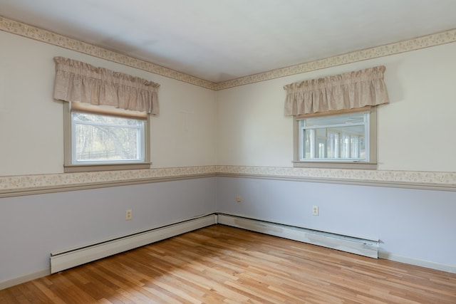 unfurnished room featuring hardwood / wood-style flooring and a baseboard heating unit