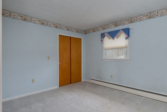 unfurnished bedroom with carpet flooring, a closet, and a baseboard heating unit