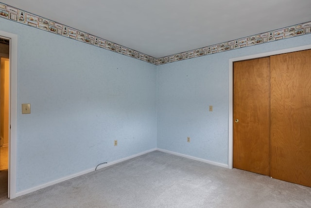 unfurnished bedroom featuring light colored carpet and a closet