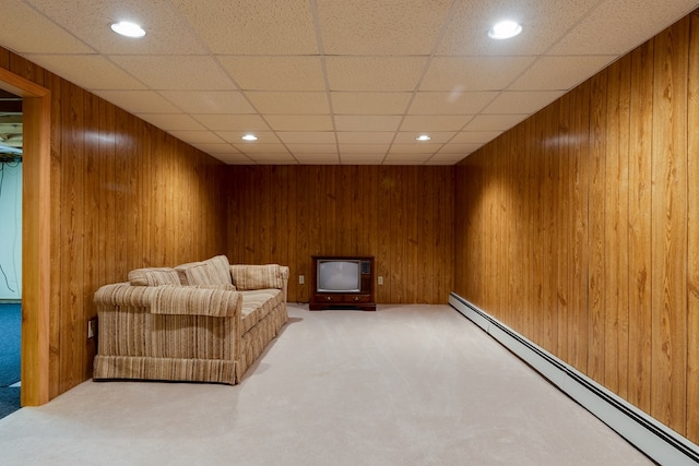 sitting room featuring carpet flooring, a paneled ceiling, a baseboard radiator, and wooden walls