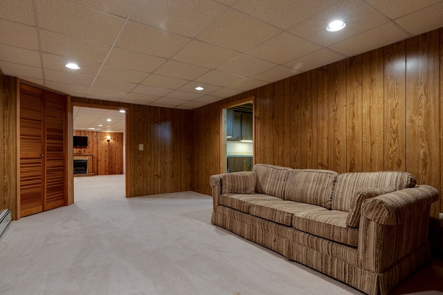 carpeted living room with a paneled ceiling and wooden walls