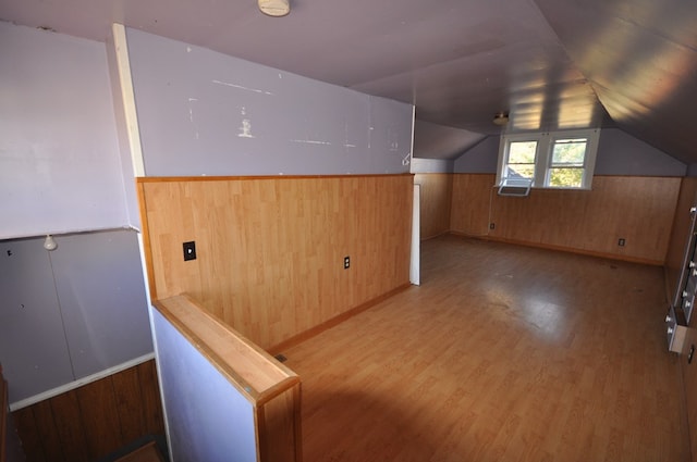 bonus room with hardwood / wood-style flooring, wooden walls, and vaulted ceiling