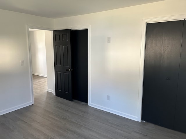 unfurnished bedroom featuring a closet and dark wood-type flooring