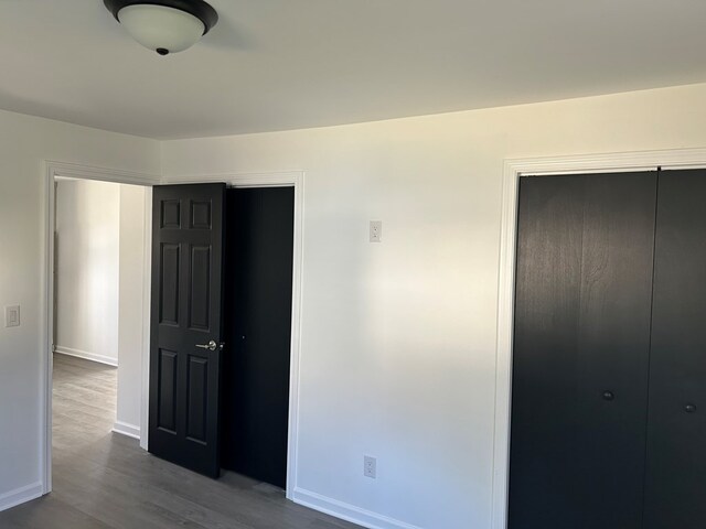 bedroom with dark hardwood / wood-style flooring and a closet