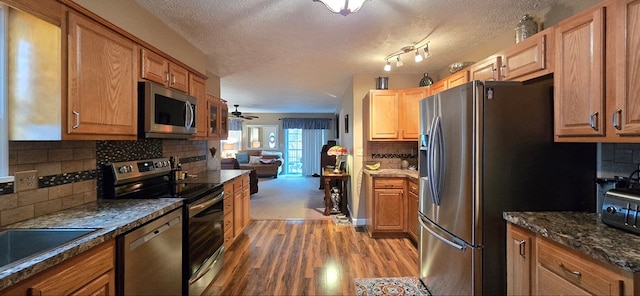 kitchen with backsplash, hardwood / wood-style flooring, ceiling fan, a textured ceiling, and stainless steel appliances