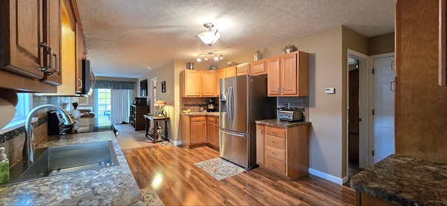 kitchen with stainless steel fridge, light wood-type flooring, tasteful backsplash, a textured ceiling, and sink