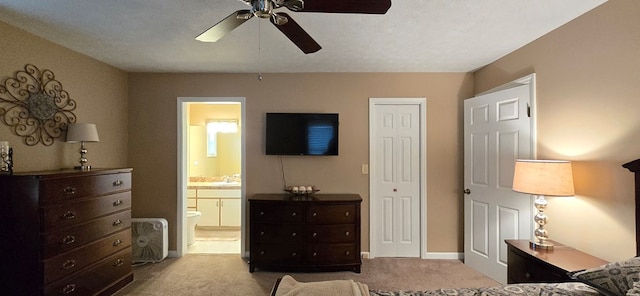 bedroom with a textured ceiling, connected bathroom, light colored carpet, and ceiling fan